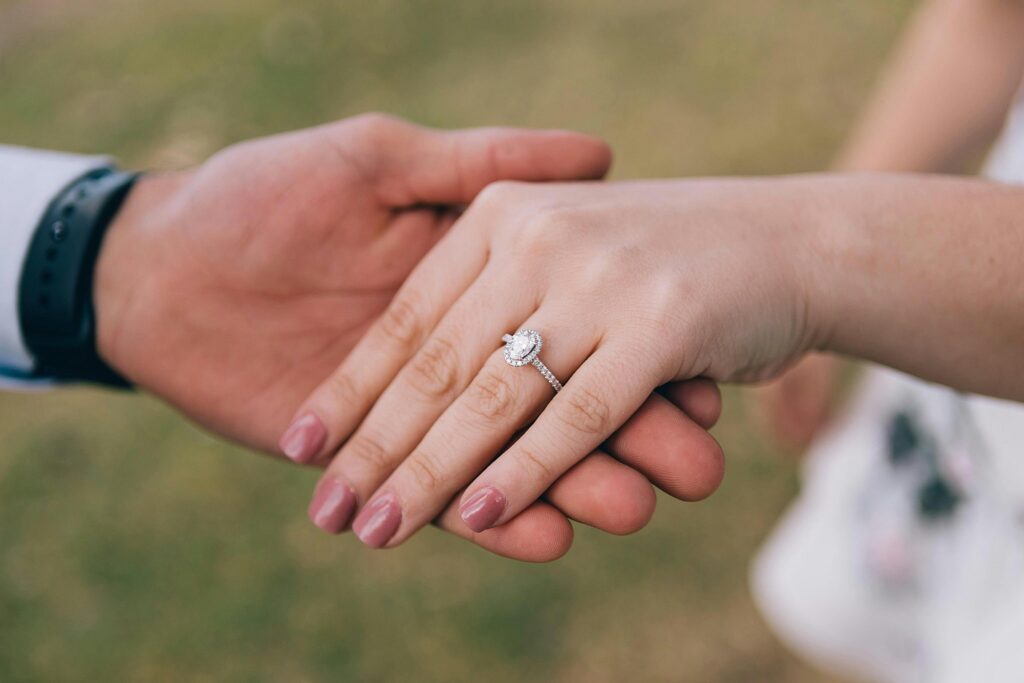 couple holding hands with engagement ring showing