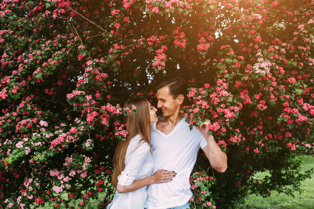 Seasonal Photo Ideas for Engagement Sessions. Young happy couple in love outdoors. loving man and woman on a walk in a spring blooming park