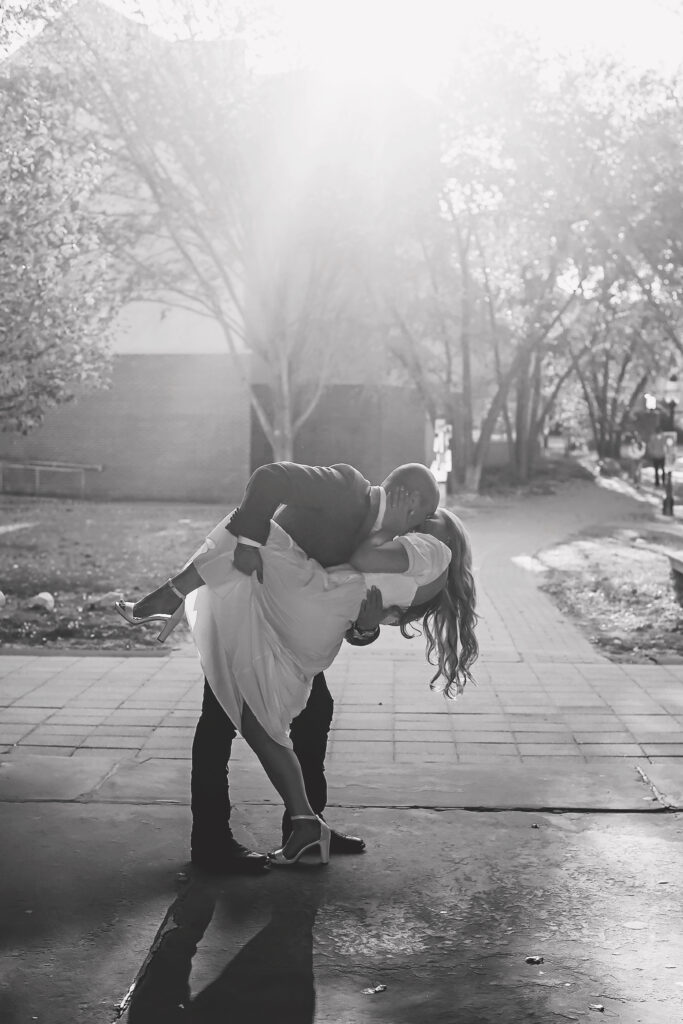 man dipping woman for a kiss in black and white